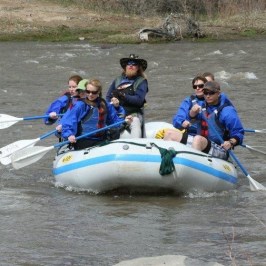 a group of people riding on the back of a boat in the water