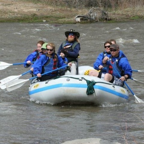 a group of people riding on the back of a boat in the water